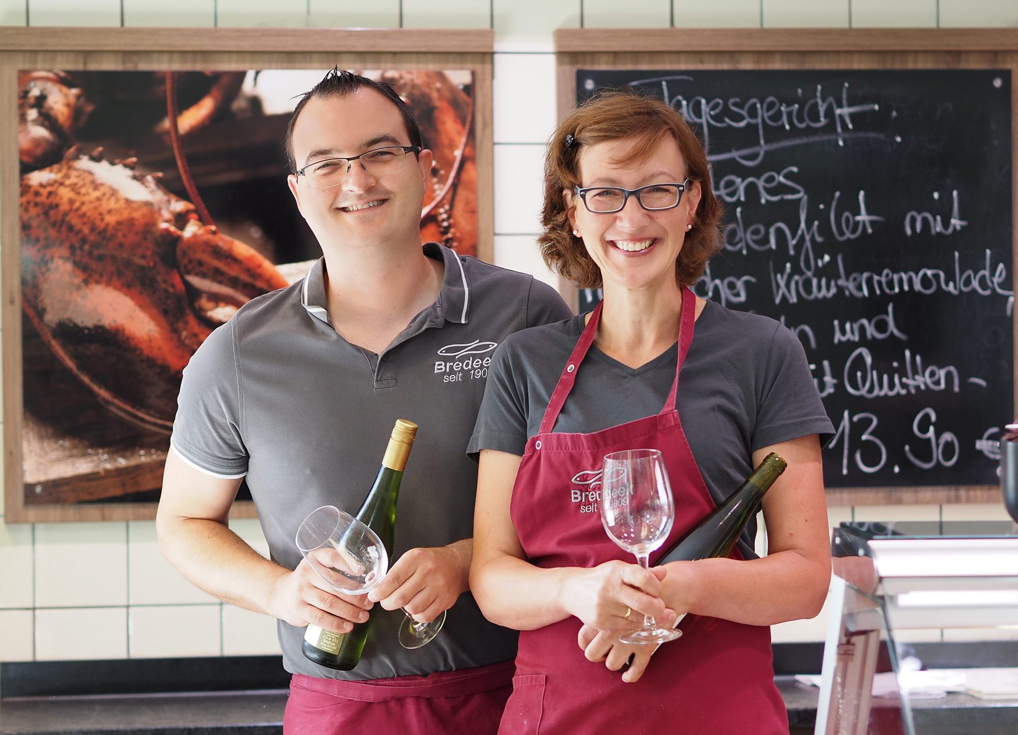 Zwei Mitarbeiter mit Wein und Gläsern
